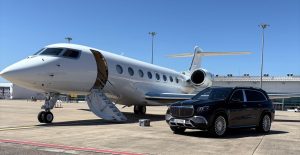 a luxury private chauffeur service with a maybach in an airport next to a private jet
