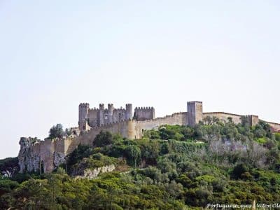 Medieval Castelo de Obidos and its walls in Portugal Medieval Castelo de Obidos and its walls seen from a hillside surrounded by trees