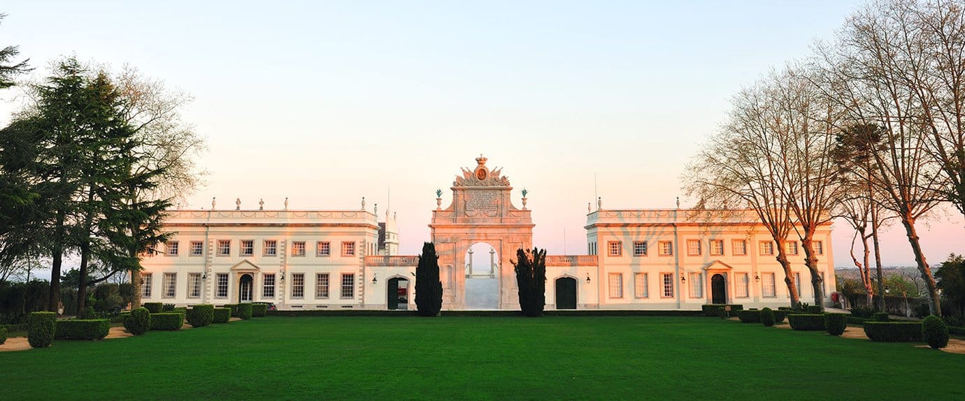 Tivoli Palacio de Seteais neoclassical hotel with triumphal arch at golden hour, wide lawn in foreground