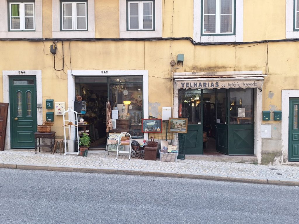 Storefront of an antique dealer on Rua de Sao Bento in Lisbon, with furniture and framed paintings displayed on the pavement