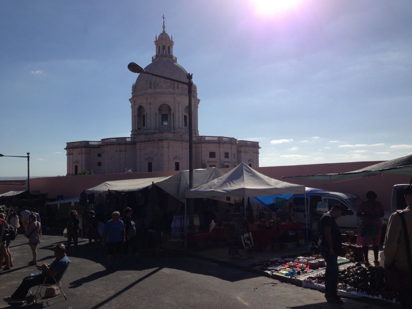 Market stalls at Feira da Ladra flea market in Lisbon, with the dome of the National Pantheon in the background
