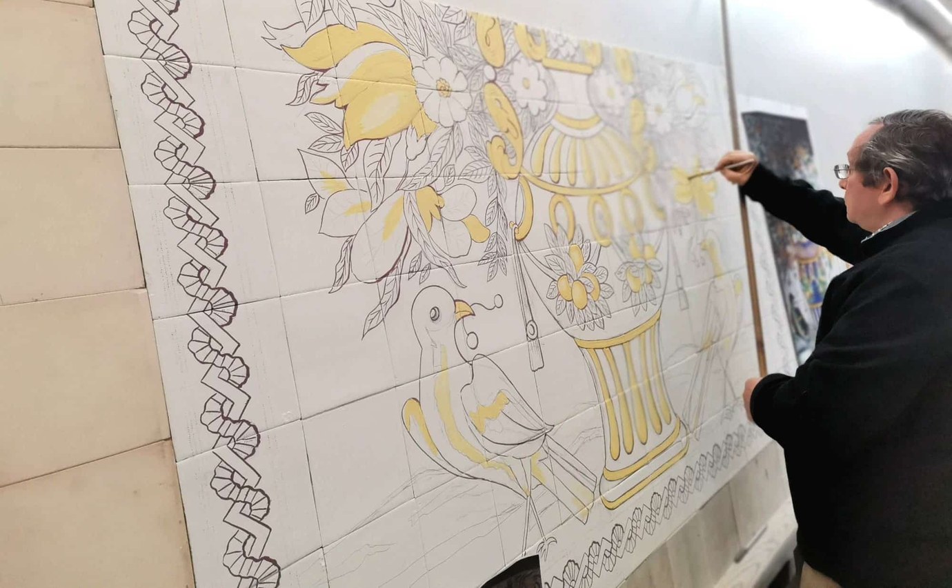 Artisan hand-painting a large azulejo tile mural at Fabrica Santanna workshop in Chiado, Lisbon