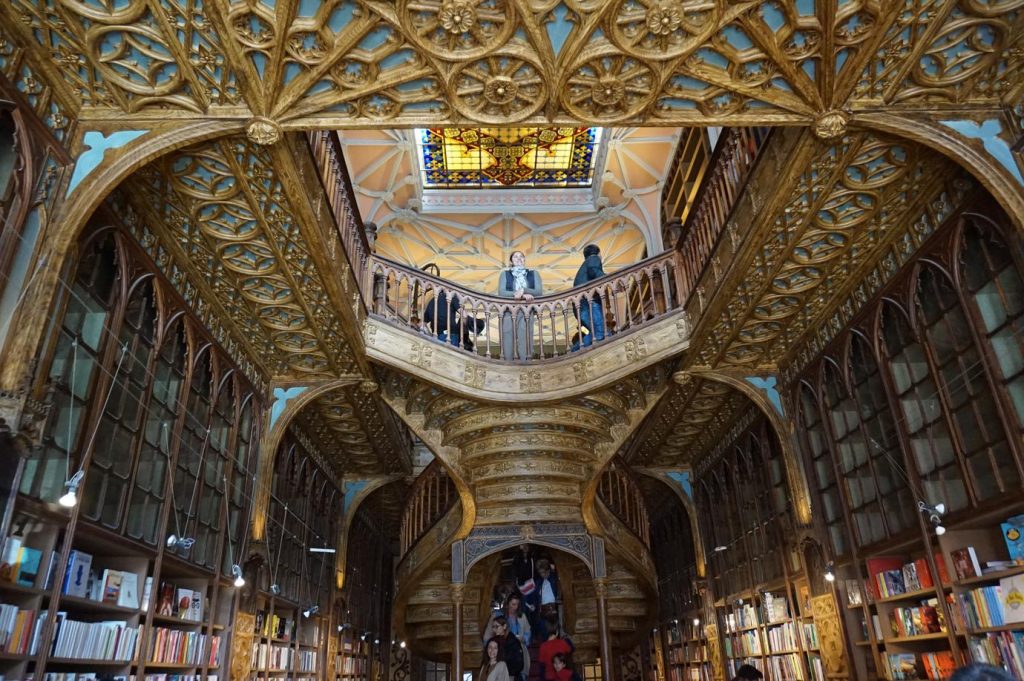 Interior of Livraria Lello in Porto showing the red staircase, skylight and bookshelves