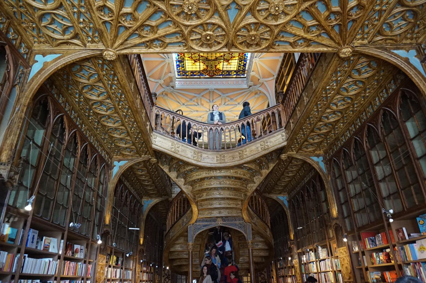 Interior of Livraria Lello in Porto showing the red staircase, skylight and bookshelves