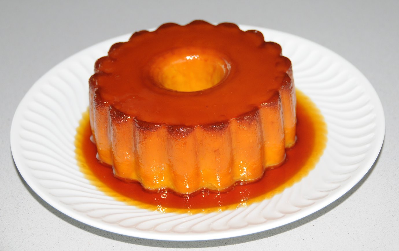 Pudim Abade de Priscos, a caramel egg pudding made with bacon and port wine, served on a white plate
