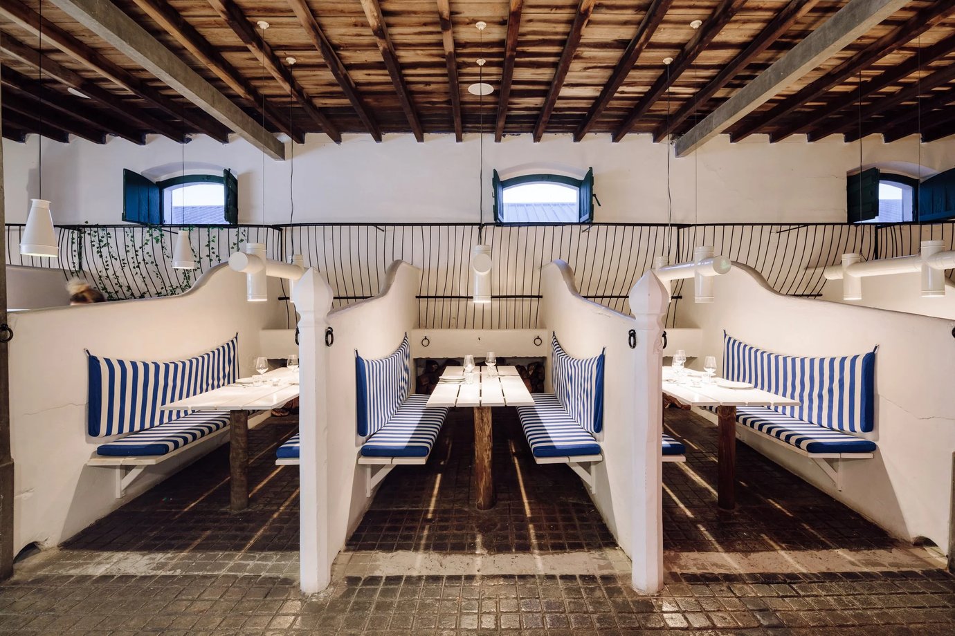 Interior of Cavalarica restaurant in Comporta, a converted horse stable with timber beams and striped banquettes