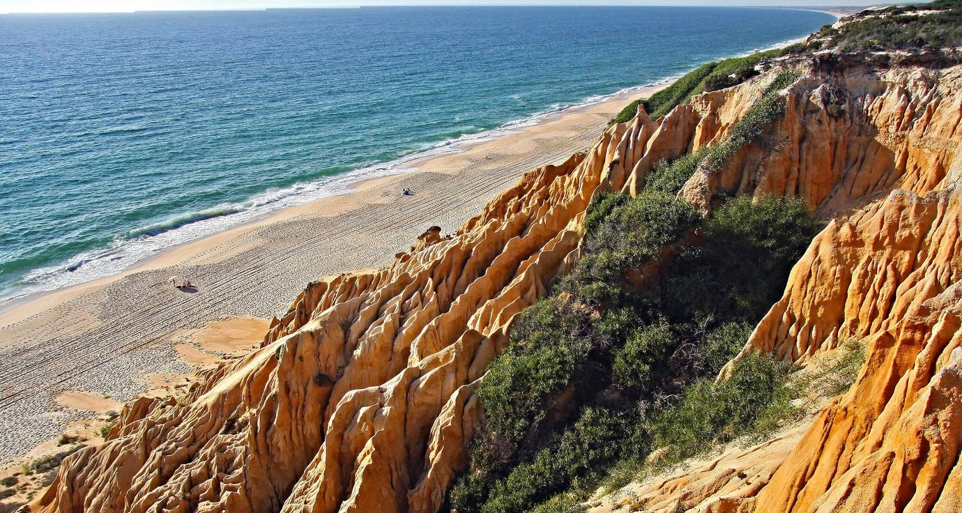 Golden fossil cliffs and empty sandy beach with turquoise water at Praia da Gale-Fontainhas, near Comporta, Portugal
