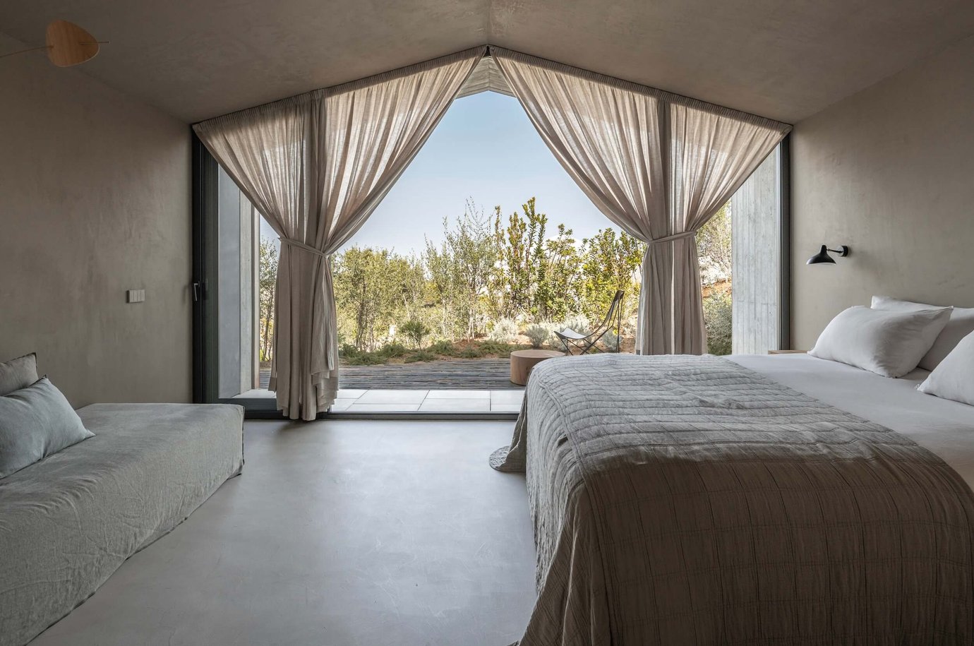 Minimalist bedroom with gabled window and linen curtains at O Pateo villa near Melides, Portugal