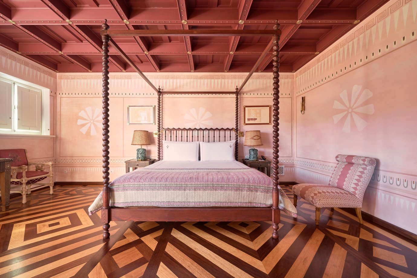 Canopy bed in a pink and terracotta-toned suite with stenciled walls and parquet floor at Vermelho hotel, Melides, Portugal