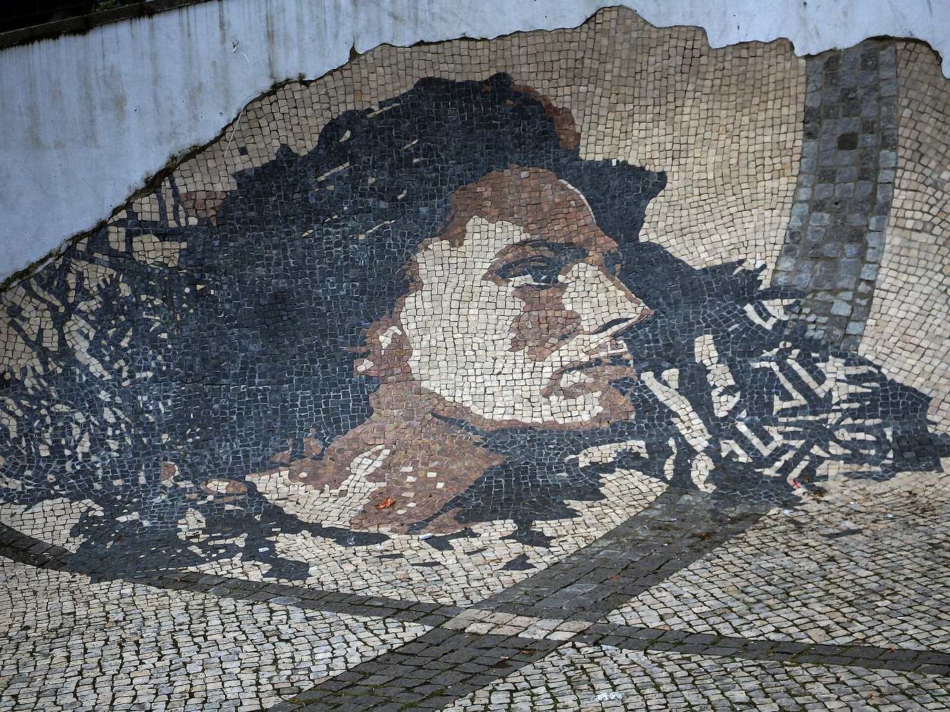 A black, white and brown pavement mosaic portrait of the fado singer Amália Rodrigues set into a cobbled slope below the castle in Lisbon