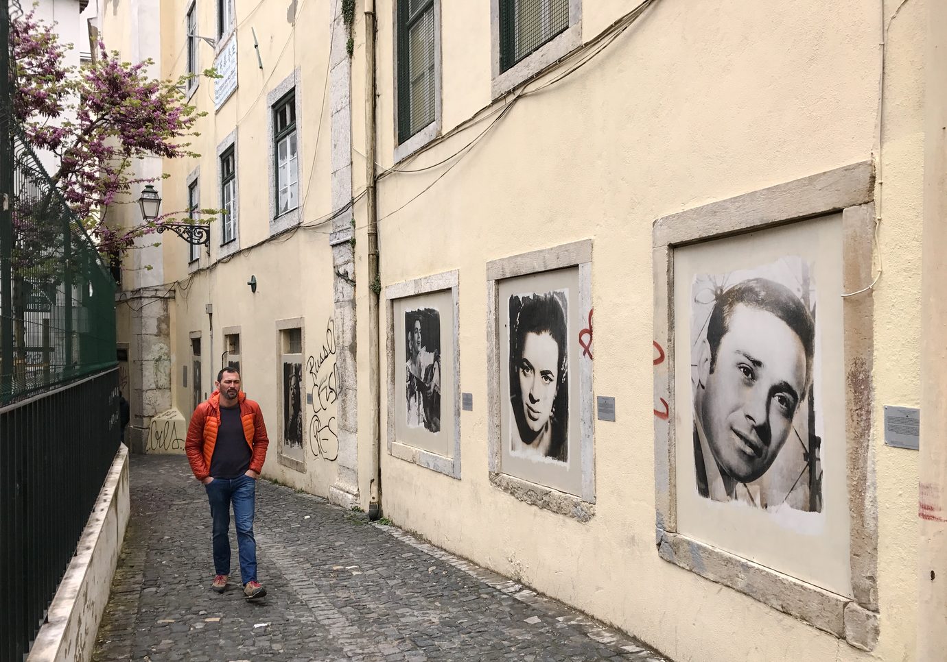 A narrow Mouraria lane in Lisbon with large black and white portraits of fado legends on a pale wall