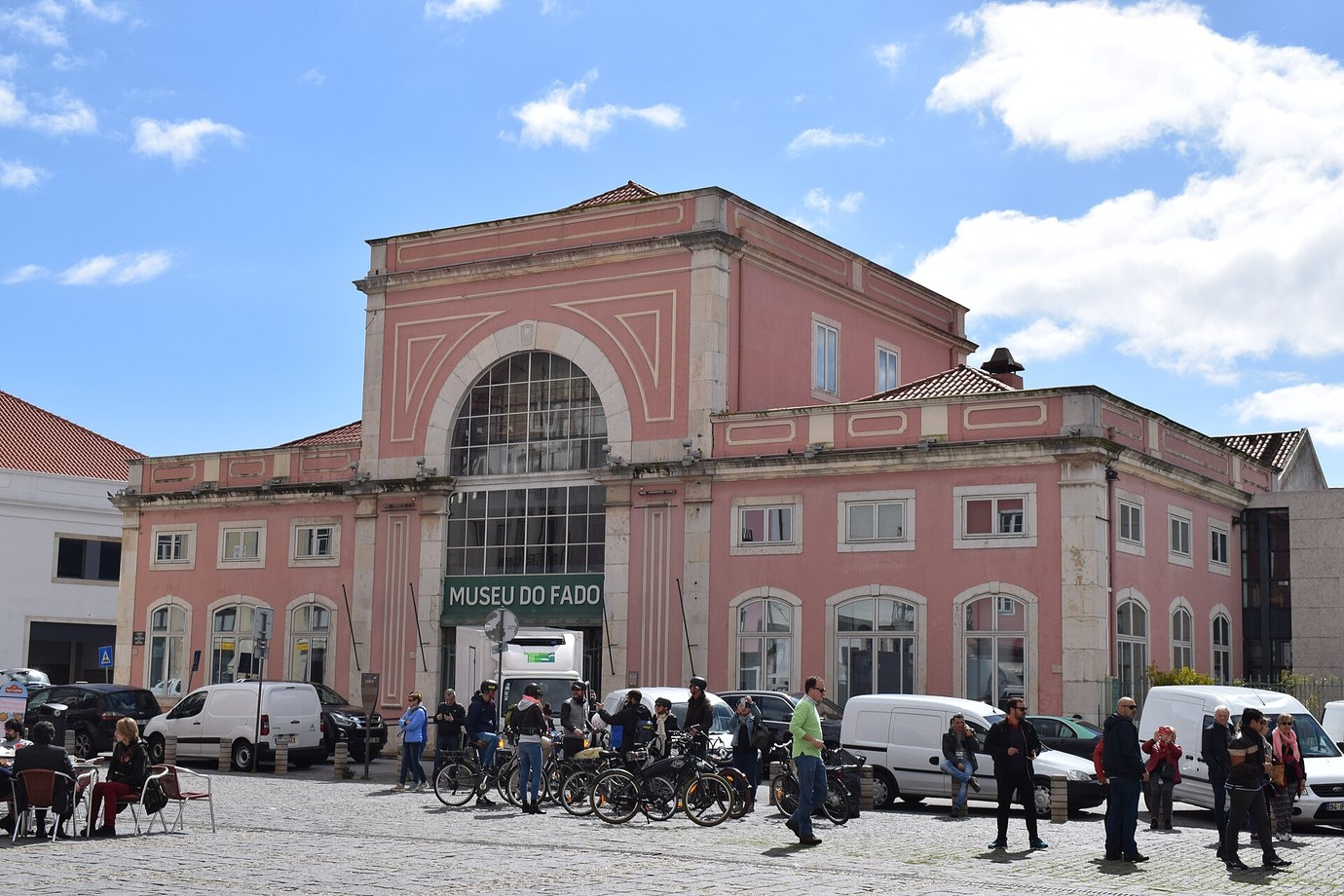 The pink neoclassical façade of the Museu do Fado on Largo do Chafariz de Dentro in Alfama under a blue sky with white clouds