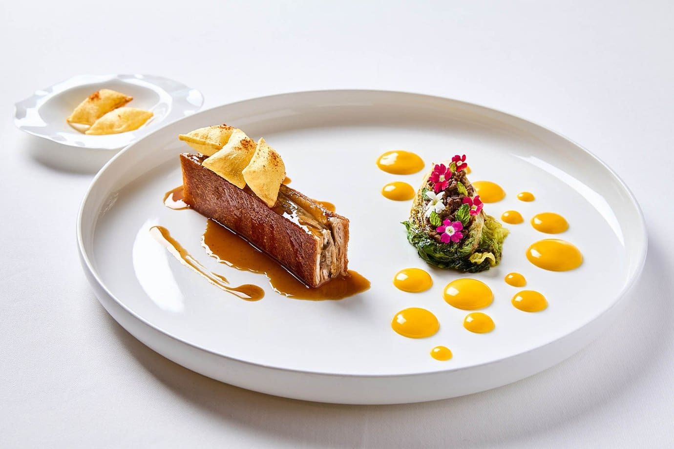 A plated tasting menu course with sauce dots and edible flowers at the Belcanto restaurant in Lisbon