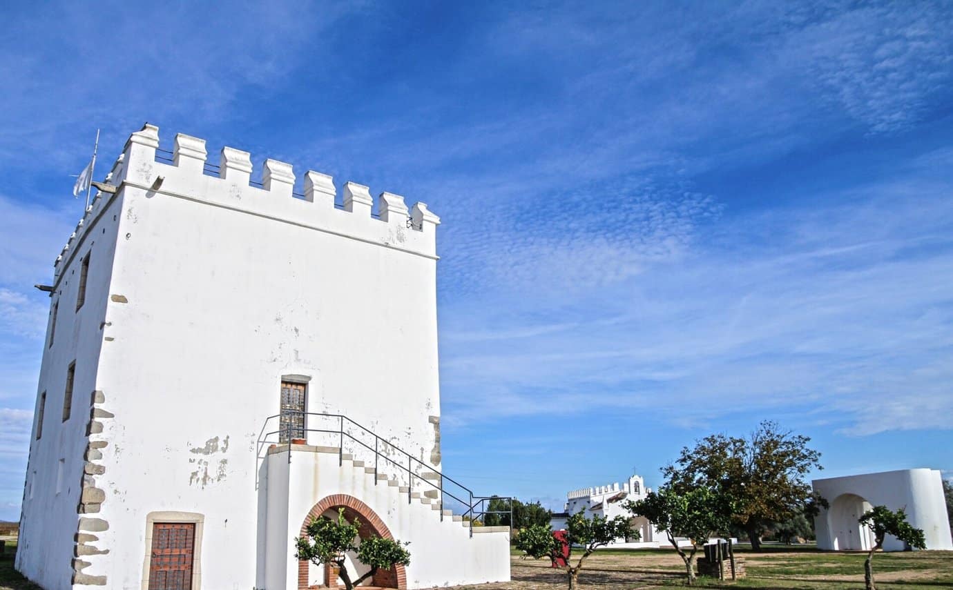 The whitewashed tower at Herdade do Esporão in the Alentejo under a deep blue sky, the wine estate home to a one-Michelin-star restaurant