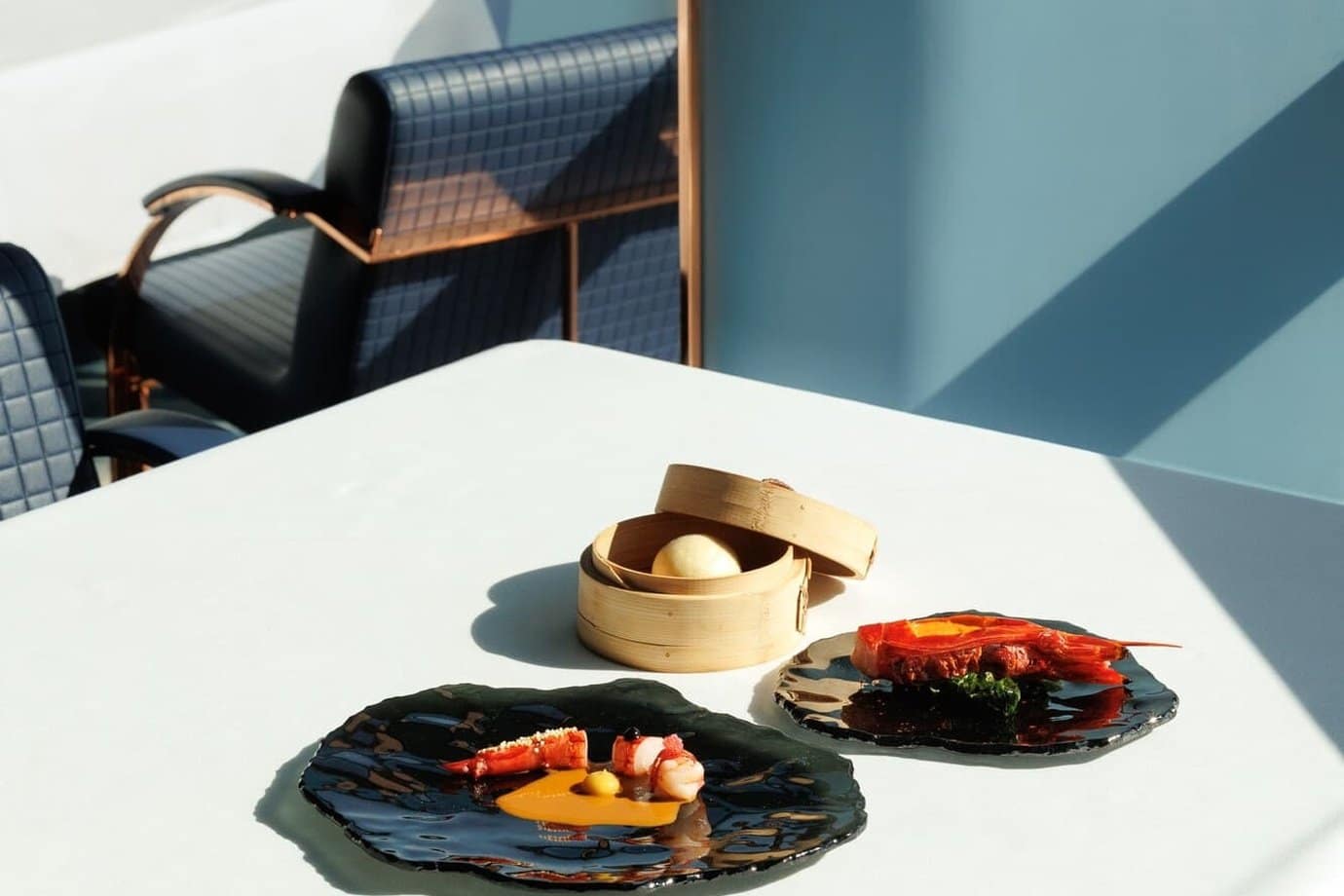 Tasting menu dishes on a sunlit table in the blue dining room of Fifty Seconds, the two-Michelin-star restaurant in Lisbon